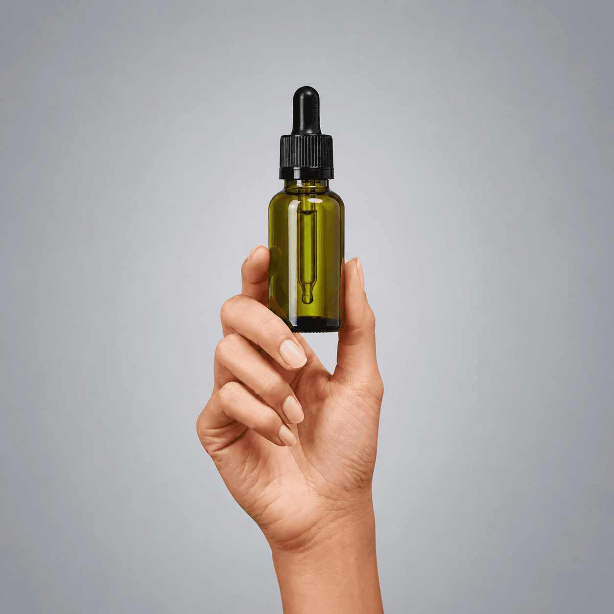A hand holding a dropper bottle representing the CBD industry