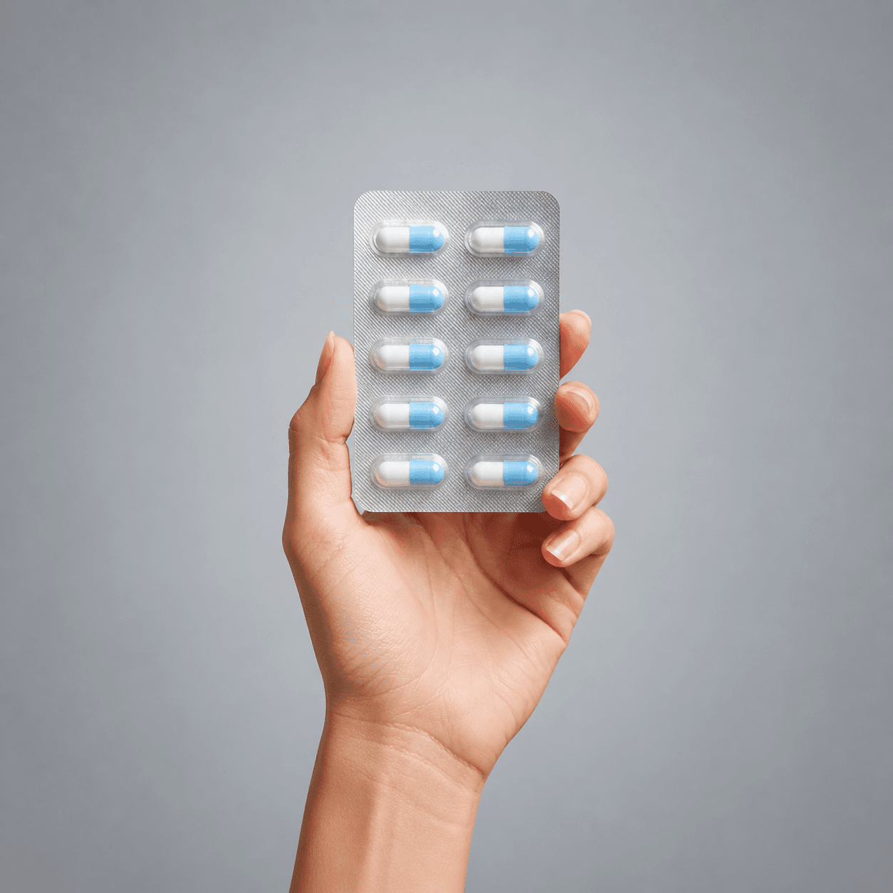 A hand holding a blister pack of pills representing the online pharmacy industry