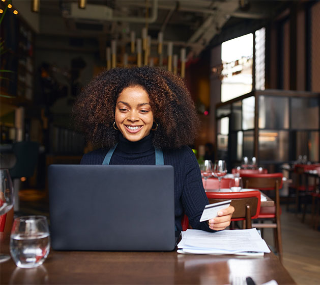 A fine dining business owner looking over business reports on her laptop thanks to American PaySave POS systems