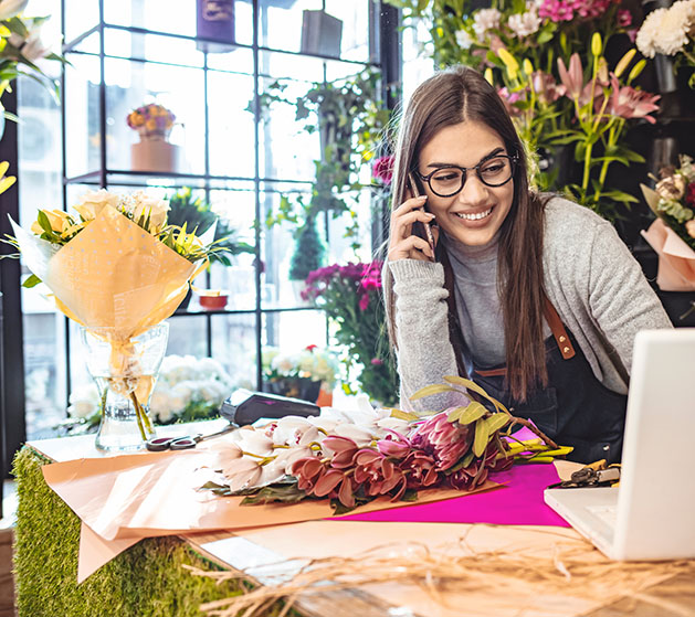 A florist smiling at how streamlined her business operations are thanks to American PaySave's POS systems