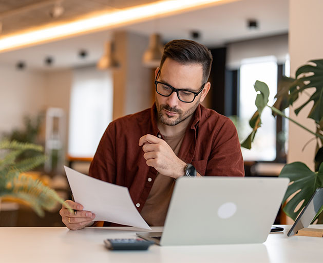A business owner reviewing paper invoice reports built using American PaySave's POS systems